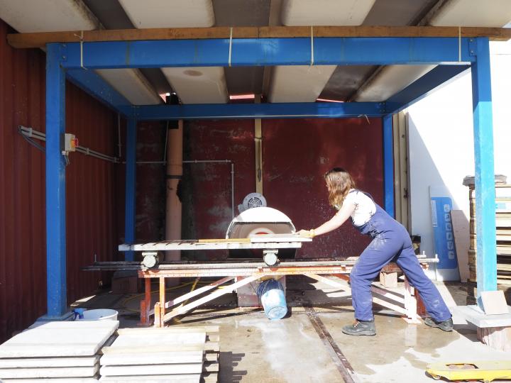 Using a large static disc grinder to clean the edges of marble slabs from residual traces of mortar.